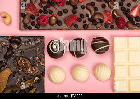 Mise à plat avec un assortiment de chocolat avec des fruits et des noix et des bonbons sur rose isolé Banque D'Images