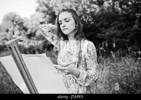 Portrait d'une jolie jeune femme en robe longue peinture à l'aquarelle dans la nature. Photo en noir et blanc. Banque D'Images