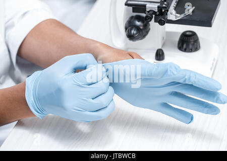Close-up vue partielle de scientifique en portant des gants protecteurs en laboratoire chimique Banque D'Images