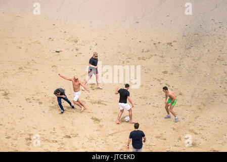 Un groupe de jeunes hommes jouant au football sur une plage à Newquay, Cornwall. Banque D'Images