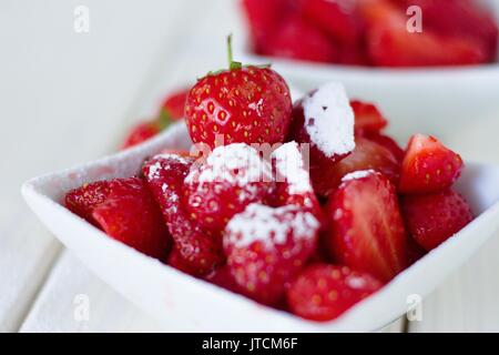 Les fraises avec du sucre en poudre dans le bol carré.Classic british summer snack Banque D'Images