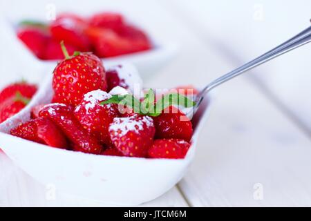 Les enfants jardin préféré snack - les fraises avec le sucre dans un bol carré blanc Banque D'Images