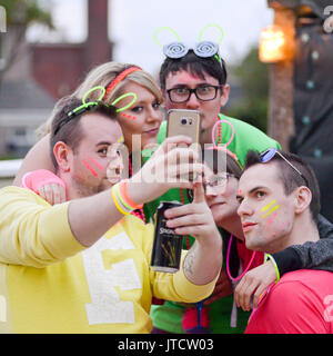 Un groupe de jeunes gens de robe de couleur vive en tenant un téléphone mobile sur un selfies. Banque D'Images