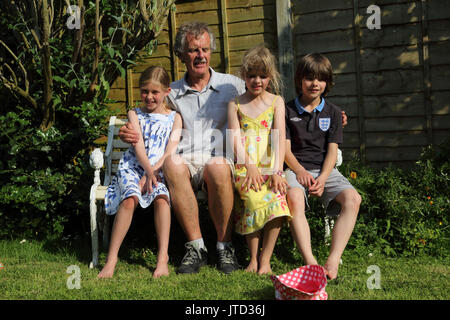 Grand-père avec ses petits-enfants assis sur un banc Smiling In jardin en été Birmingham West Midlands England Banque D'Images