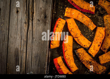 Des plats traditionnels de l'automne à partir de la citrouille. Fried cuits sur grill potiron avec les épices, l'huile d'olive, des herbes. Sur une plaque, sur une vieille table en bois rustique. T Banque D'Images