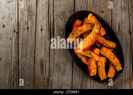 Des plats traditionnels de l'automne à partir de la citrouille. Fried cuits sur grill potiron avec les épices, l'huile d'olive, des herbes. Sur une plaque, sur une vieille table en bois rustique. T Banque D'Images