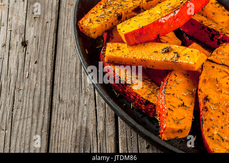 Des plats traditionnels de l'automne à partir de la citrouille. Fried cuits sur grill potiron avec les épices, l'huile d'olive, des herbes. Sur une plaque, sur une vieille table en bois rustique. C Banque D'Images