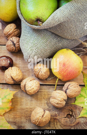 Composition d'automne de fruits, de noix et d'épices - Poires, Noix, feuilles d'érable sur un fond de bois toning Banque D'Images
