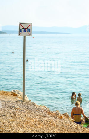 Split, CROATIE - le 24 juin 2017 : un pas de chiens en signe de la mer avec des gens se baigner et prendre le soleil sur la plage de la mer à Njivice, île de Krk, Croatie. Banque D'Images