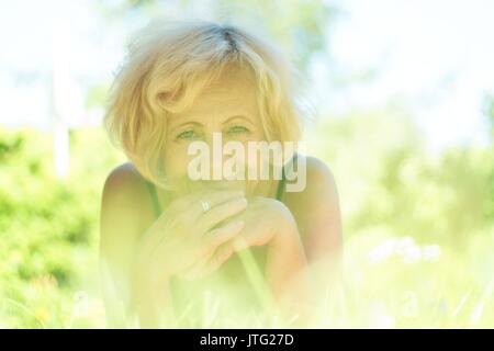 Happy middle-aged woman lying in the grass Banque D'Images