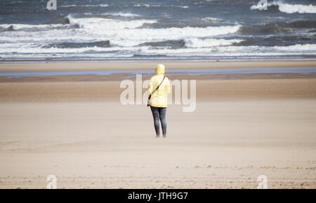 Vue arrière d'une femme sur la plage, vue sur la mer par une journée de vent brillant. Isolement, solitude, dépression féminine, distanciation sociale... concept. Banque D'Images