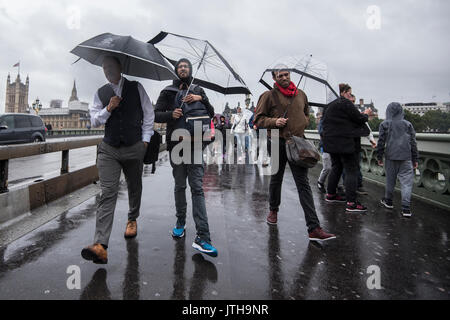 Londres, Royaume-Uni. 9 Août, 2017. Les touristes et les banlieusards à travers le pont de Westminster à Londres, au Royaume-Uni que heavy rain frappe la ville. Crédit : Ben Furst/Alamy Live News. Banque D'Images