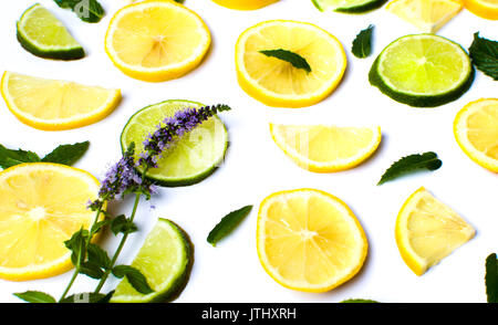 Les tranches de citron et de citron vert avec des feuilles de menthe sur blanc Banque D'Images