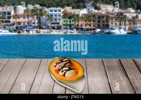Billes de melon rempli de glace et garnir sur une table en bois. Dans l'arrière-plan bleu de la mer et une ville portuaire de la Méditerranée. Banque D'Images