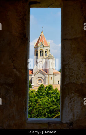 Une vue de l'abbaye de Lérins dans l'île Saint-Honorat, France, mettant en évidence la tour lanterne de son église, vu à travers une meurtrière d'un stone wal Banque D'Images