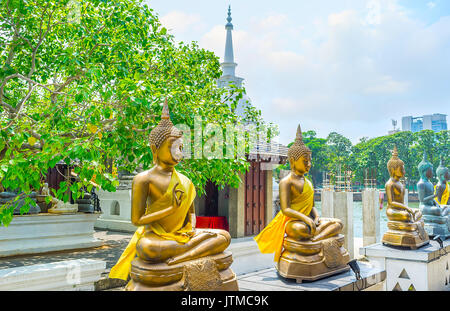 Les statues en or de Bouddha assis à l'ombre de l'arbre de Bodhi de Seema Malaka Temple avec la flèche de Stupa sur arrière-plan, Colombo, Sri Lanka. Banque D'Images