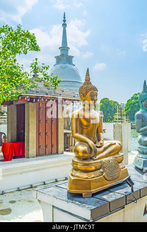 Le Stupa blanc derrière la statue en or de Bouddha de toucher terre à Seema Malaka Temple du complexe Gangaramaya, Colombo, Sri Lanka. Banque D'Images