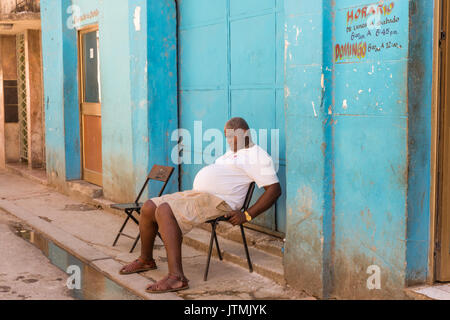 L'heure de la sieste, l'homme cubains dormir sur une chaise dans une scène de rue dans la Vieille Havane, Cuba Banque D'Images