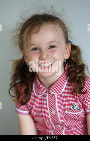 Isabelle, 5, photographié dans son uniforme de l'école après sa première dent est tombée à son domicile à Sussex, UK. Banque D'Images