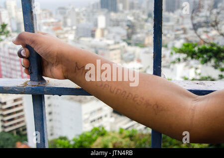 Un message écrit sur un bras de la jeune fille qui se traduit par 'I miss you mum'. Prise lors d'une favela de Rio Banque D'Images