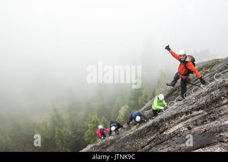 Un groupe de personnes profitez d'une via ferrata sur une journée d'automne pluvieuse Squamish (Colombie-Britannique). Banque D'Images