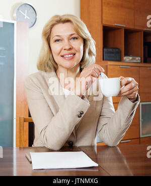 Femme mature avec une tasse de thé à la table Banque D'Images