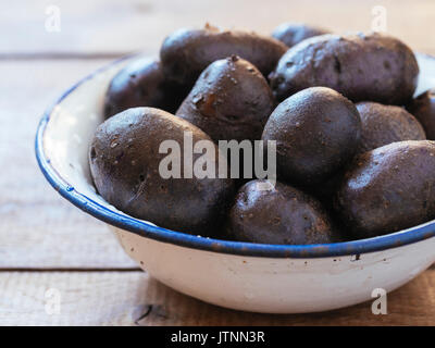 Violet lavé les pommes de terre (type : Bergerac) dans un bol Banque D'Images