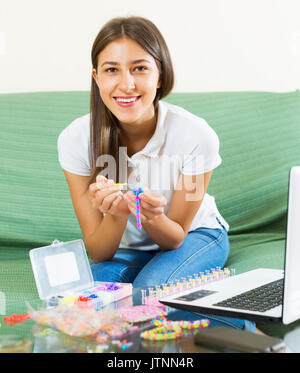 Souriante jeune fille fait braslets avec bandes élastiques rainbow loom Banque D'Images