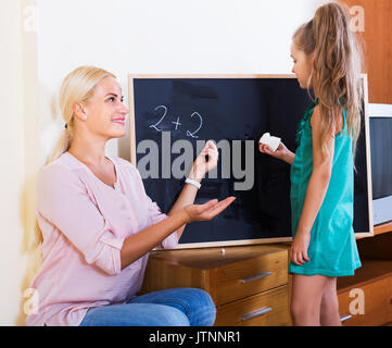 Mère et fille heureux faisant somme at blackboard Banque D'Images