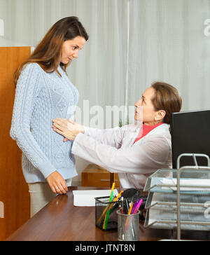 Femme médecin touchant l'estomac de jeune fille dans la chambre Banque D'Images