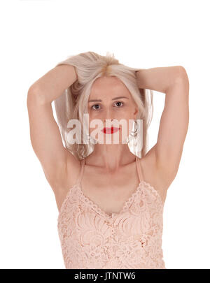 Une belle jeune femme debout à l'avant avec ses deux mains sous ses cheveux blonds, mettre le bazar, isolée pour fond blanc Banque D'Images