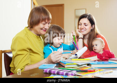 Femme heureuse avec sa fille et petits-enfants une esquisse sur papier à table. L'accent sur la maturité Banque D'Images