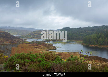 De superbes paysages des Highlands sur matin brumeux avec petite route sinueuse traversant loch sous ciel d'orage près de Achmelvich, Ecosse Banque D'Images