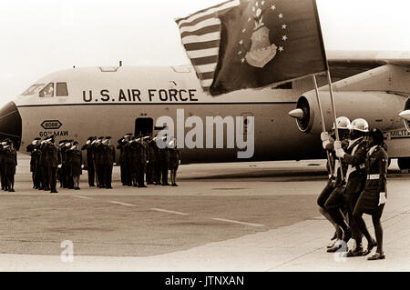 Une armée de l'air sur la garde d'honneur salue les drapeaux qu'ils sont exhibés aux côtés d'un C-141 Starlifter qui transportait les restes de prisonniers de guerre et de MIA le nord du Vietnam. Banque D'Images