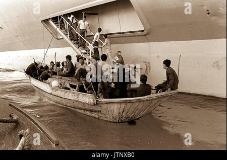 Réfugiés vietnamiens se préparent à venir à bord du USS Blue Ridge (LCC-19). Les réfugiés ont été secourus par le navire de commandement amphibie 350 milles au nord-est de la baie de Cam Ranh, Vietnam, après huit jours en mer dans un bateau de pêche de 35 pieds. Banque D'Images