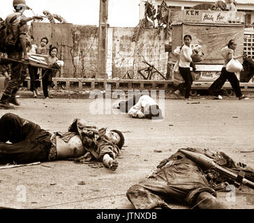 Avec la peur et l'appréhension montrant sur leur visage, et à la demande de troupes vietnamiennes du sud, les femmes et les enfants sont chargés de biens récupérés se précipitent au-delà du corps de trois Viet Cong tués dans les combats. Mai 1968. (USIA) DATE EXACTE INCONNUE SHOT #  FICHIER NARA : 306-MVP-4-4 LIVRE Guerres et conflits #  : 423 Banque D'Images