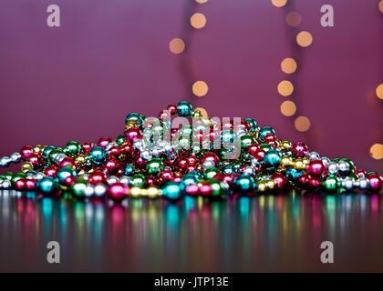 Pile de multi colored Christmas garland avec reflets et Lumières floues en arrière-plan Banque D'Images