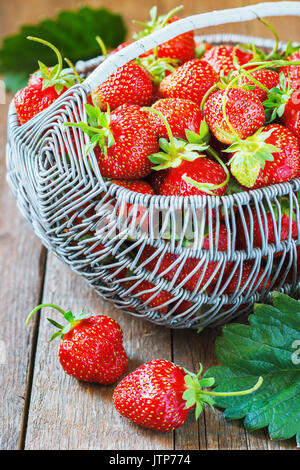 Fraises fraîches juteux dans un panier sur fond de bois, selective focus. Banque D'Images