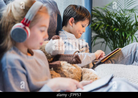 Vue de côté de l'accent petit garçon et fille dans les écouteurs sous digital tablets Banque D'Images