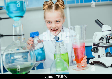 Lycéenne en blouse blanche faisant expérimenter avec réactifs dans un laboratoire de sciences Banque D'Images