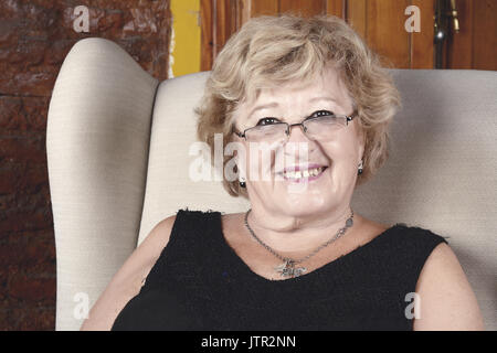 Portrait d'une vieille femme assise sur le canapé. À l'intérieur. Banque D'Images