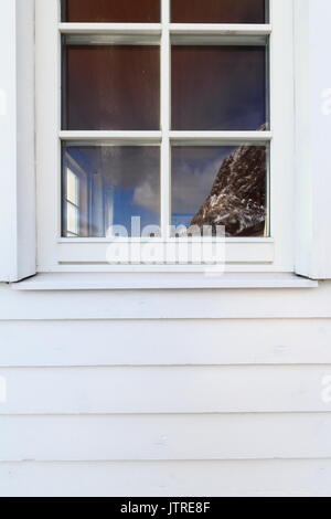 Festhaeltinden montage reflète dans la fenêtre d'un blanc rorbuer-traditionnelle pêche saisonnière chalet-maintenant pour des utilisations touristiques-côté ouest de la pêche à la p Banque D'Images