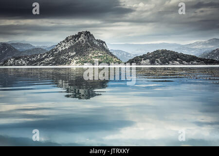 Lac tranquille avec de l'eau reflet du ciel et paysage Montagnes Ciel couvert en journée avec ciel dramatique en Europe pays Monténégro au lac Skadar Banque D'Images