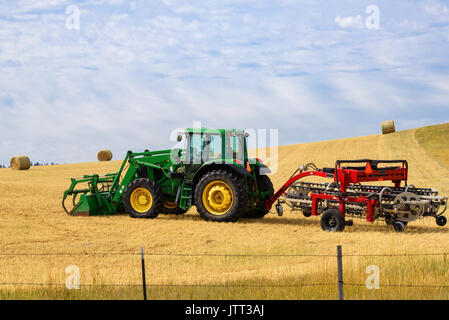 Dans le domaine du tracteur avec un râteau râteau foin.. ci-joint fond de ciel bleu. Banque D'Images