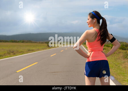 Road Runner chinois asiatique debout sur l'asphalte des rues prêt pour l'entraînement de course long monter d'entraînement dans l'après-midi de la sunshine portant headphon Banque D'Images