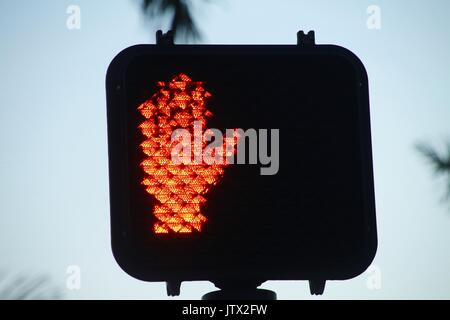 Arrêt lumineux rouge ne marche pas main Signal à Carrefour en face de palmiers et ciel bleu clair après le crépuscule Banque D'Images