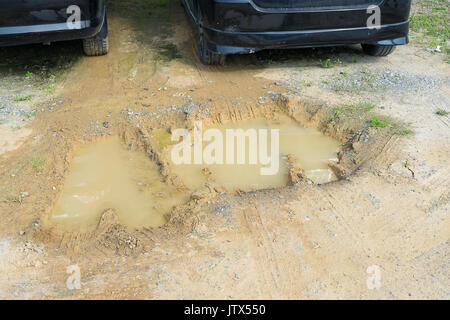 La largeur de voie dans la boue ou la voiture embourbée, fragment rut embourbé dans la boue dans le parking. Banque D'Images