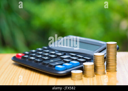 De plus en plus d'épargne, des crédits et une calculatrice sur bois avec arbre vert arrière-plan flou. La croissance financière, d'économiser de l'argent, la richesse et le succès de l'entreprise financement de co Banque D'Images