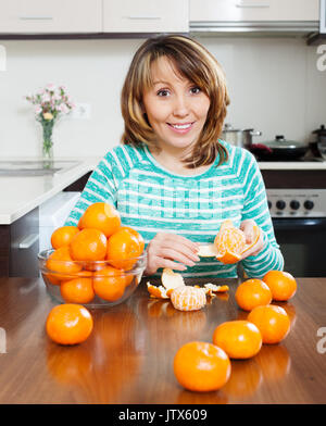 Femme avec des mandarines dans la cuisine Banque D'Images