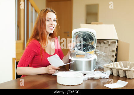 Happy woman reading carte de garantie pour les nouveaux slo-cuisinière à l'intérieur d'accueil Banque D'Images